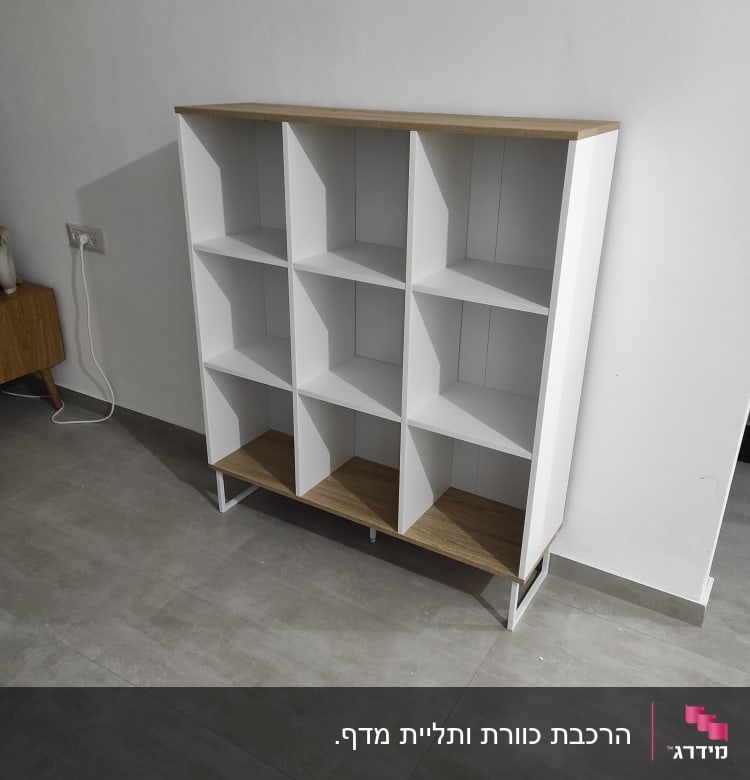 ארון מדפים לבן עם מדפי עץ, עומד על רצפה אפורה